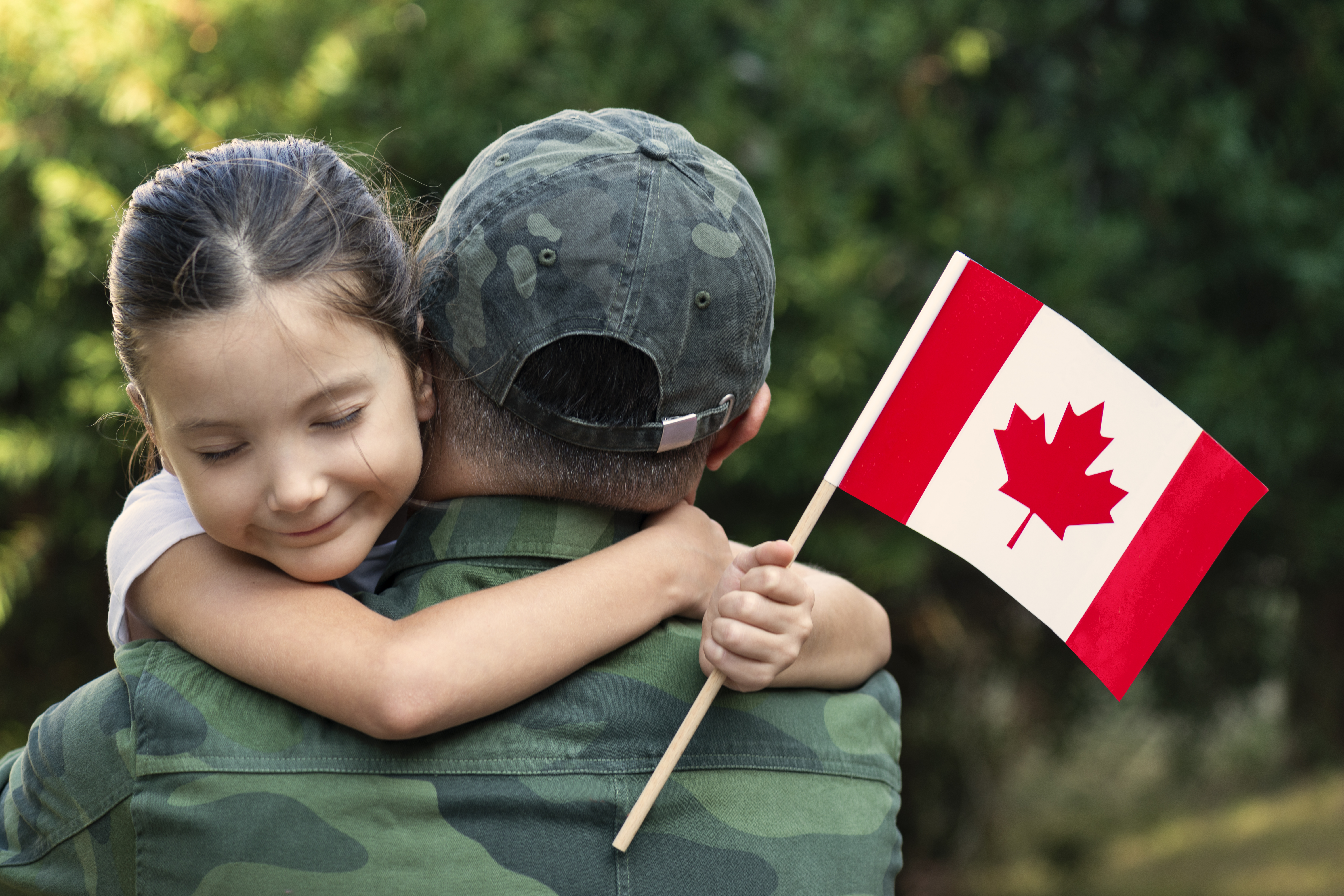 Girl hugging military parent and holding Canadian flag.
