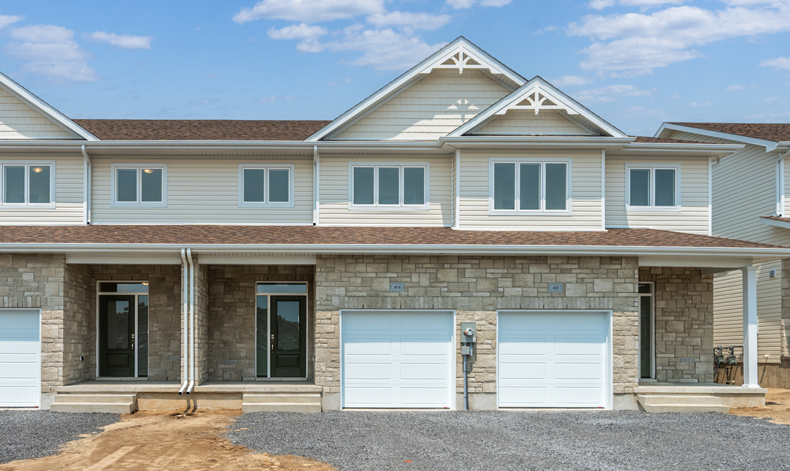 A two-storey townhome with a garage and peaked roof.