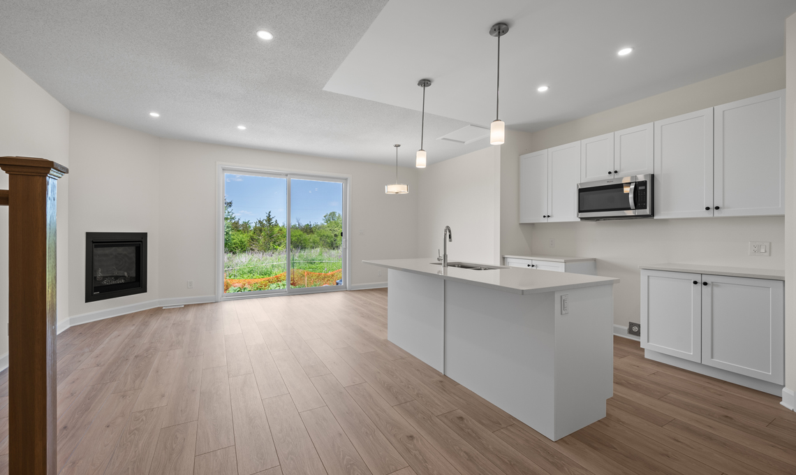 An open and spacious kitchen and living room, featuring a kitchn island and a fireplace.