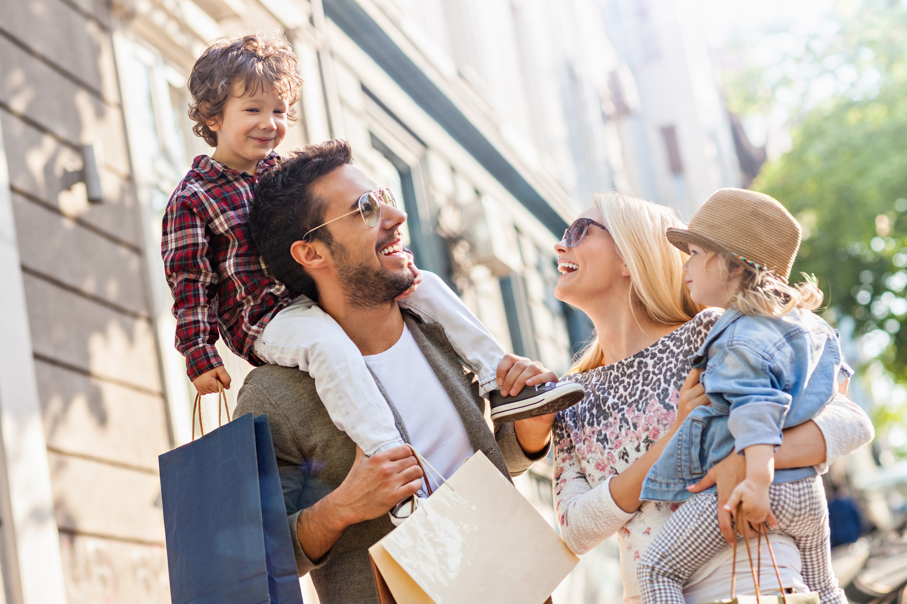 Two parents and their two children laugh and smile in the sunshine.