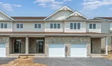 A two-storey townhome with a garage and peaked roof.